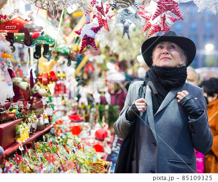 Smiling aged woman walking at traditional city christmas fair Smiling aged woman walking at traditional city christmas fair 85109325