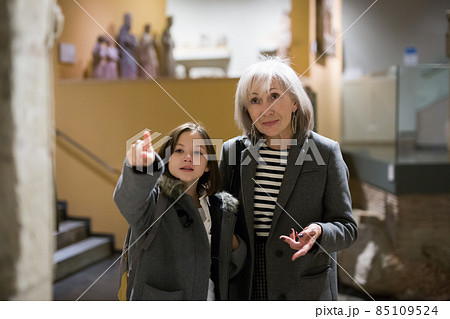 Aged female tutor with preteen girl exploring showpieces in museum Aged female tutor with preteen girl exploring showpieces in museum 85109524