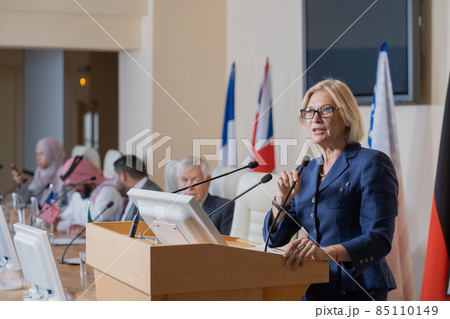 Mature female speaker in elegant suit making report 85110149