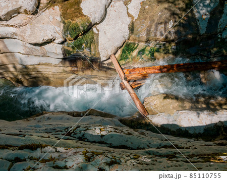 A foamy, turbulent river flows in a narrow gorge between the canyons through large logs. Top view A foamy, turbulent river flows in a narrow gorge between the canyons through large logs. Top view 85110755