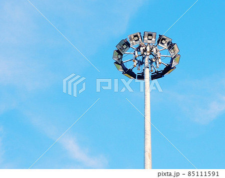 High lamppost with many spotlights in a circle against the blue sky High lamppost with many spotlights in a circle against the blue sky 85111591