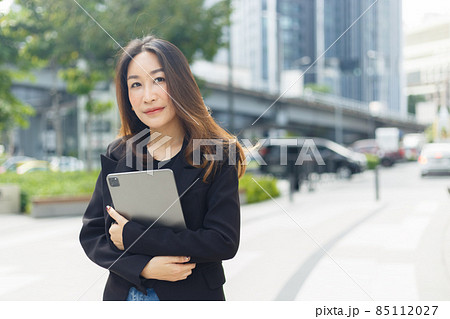 successful asian businesswoman wear black suit holding tablet walking city street. successful asian businesswoman wear black suit holding tablet walking city street. 85112027