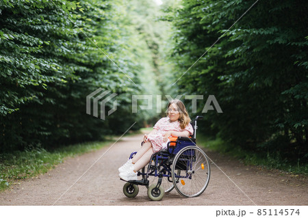 Female wheelchair user posing at summer park 85114574