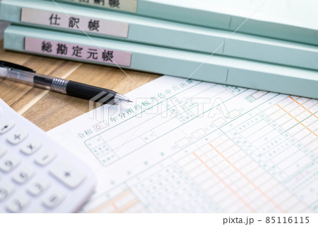 机に並べられた青色申告決算書と計算器とペンとファイル 机に並べられた青色申告決算書と計算器とペンとファイル 85116115