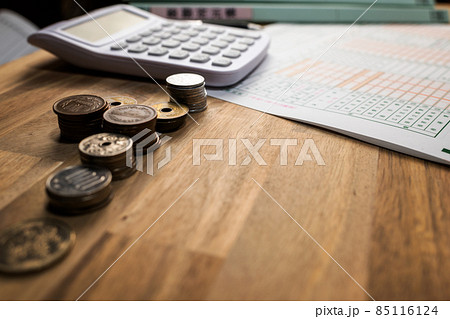机に並べられた青色申告決算書と計算器とペンとファイルと小銭 85116124