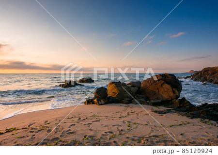 huge stones on the sandy beach at sunrise. wonderful velvet season vacation on the black sea in morning light. calm waves washing the shore of bulgaria. glowing clouds on the blue sky above horizon huge stones on the sandy beach at sunrise. wonderful velvet season vacation on the black sea in morning light. calm waves washing the shore of bulgaria. glowing clouds on the blue sky above horizon 85120924