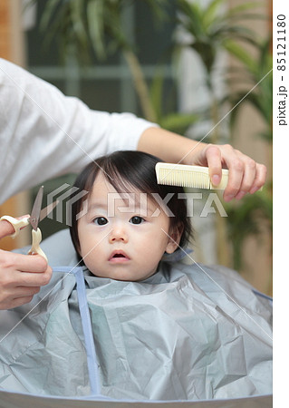 ママに前髪を切って貰う赤ちゃんの女の子の写真素材