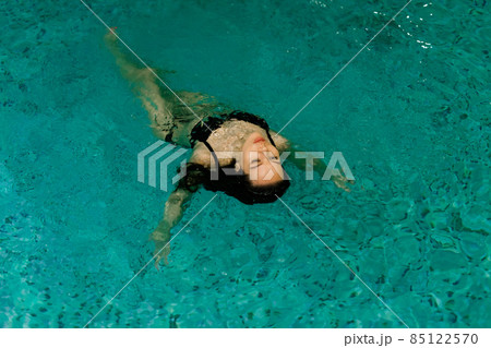 Portrait of beautiful woman in swimwear relaxing in swimming pool spa. 85122570