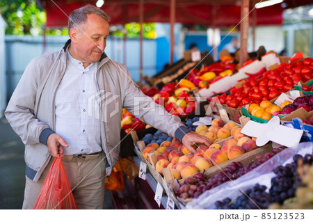 Man choosing peaches in market Man choosing peaches in market 85123523