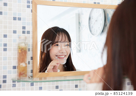 鏡の前でマウスピース矯正を付ける女性 85124139