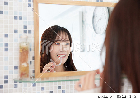 鏡の前でマウスピース矯正を付ける女性 85124145