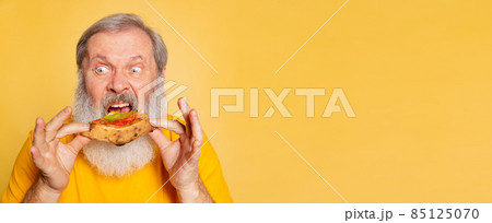 Flyer with senior funny man bites off a piece of pizza isolated on yellow studio background. World pizza day Flyer with senior funny man bites off a piece of pizza isolated on yellow studio background. World pizza day 85125070