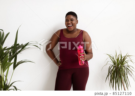 Joyful african american lady plus size holding bottle with water 85127110
