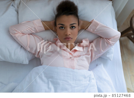 Tired african american woman suffering from depression and stress, lying on white bed at home, top view Tired african american woman suffering from depression and stress, lying on white bed at home, top view 85127468
