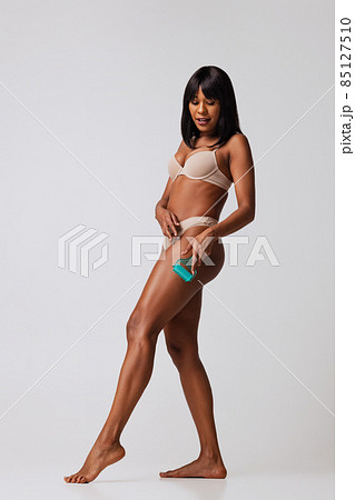 Full-length portrait of young beautiful slim girl in white underwear posing isolated over gray studio background. Natural beauty concept. Full-length portrait of young beautiful slim girl in white underwear posing isolated over gray studio background. Natural beauty concept. 85127510