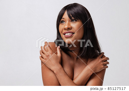 Close-up adorable dark skinned girl in white underwear smiling isolated over gray studio background. Natural beauty concept. Close-up adorable dark skinned girl in white underwear smiling isolated over gray studio background. Natural beauty concept. 85127517