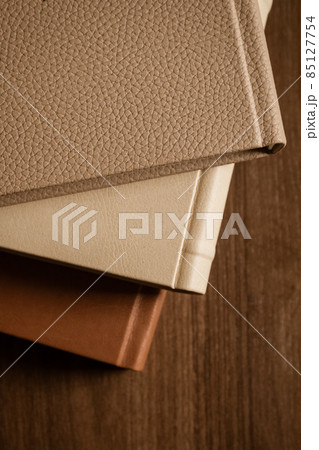 Stack of leather bound books against wooden background 85127754