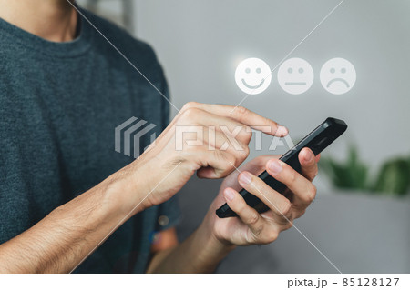 Man customer touching smartphone screen on the happy Smile face icon to give satisfaction. Review, Service rating, satisfaction, Customer service experience, and satisfaction survey concept. 85128127