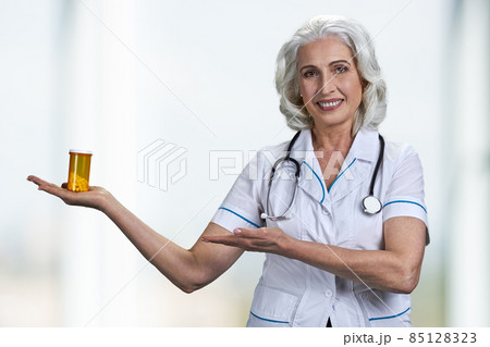 Happy mature woman doctor showing bottle of pills. 85128323