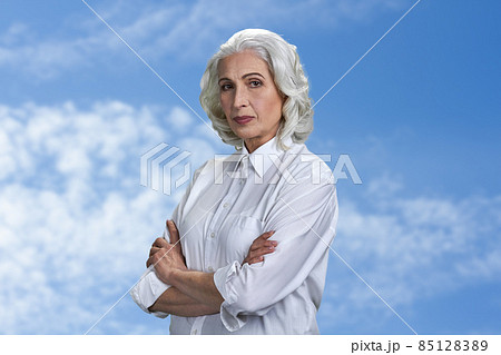 Portrait of beautiful senior woman looking at camera with crossed arms. 85128389