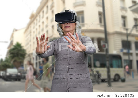 Old lady shocked experiencing virtual reality headset. 85128405