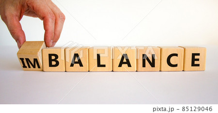 Balance or imbalance symbol. Businessman turns cubes and changes the word imbalance to balance. Beautiful white background, copy space. Business, balance or imbalance concept. Balance or imbalance symbol. Businessman turns cubes and changes the word imbalance to balance. Beautiful white background, copy space. Business, balance or imbalance concept. 85129046