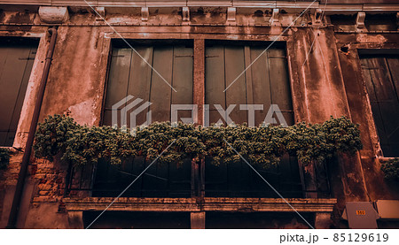 Closed brown wooden shutters in an old shabby orange building 85129619