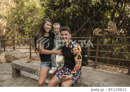 Monkeys are sitting behind people family with a child 85129621
