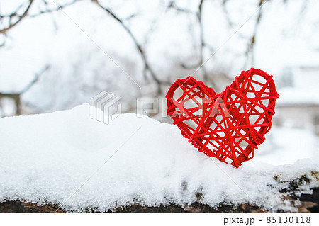 Wooden red heart on background of snow-covered tree branches. Eco-friendly valentines day. Handmade gift. Symbol of caring for nature. Wooden red heart on background of snow-covered tree branches. Eco-friendly valentines day. Handmade gift. Symbol of caring for nature. 85130118