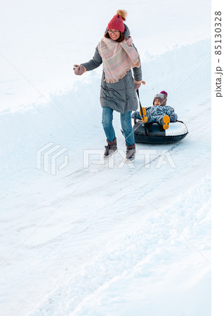 Family mom and child winter activity together on snow tubing on 85130328