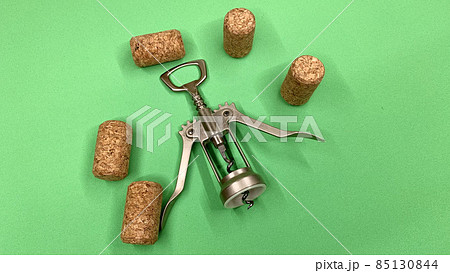 Steel wine corkscrew together with wooden corks lie on the chromakey table 85130844