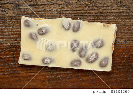 piece of white chocolate with almonds on wood piece of white chocolate with almonds on wood 85131266