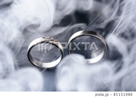 Two golden wedding rings with white smoke around, copy space and black background 85131986