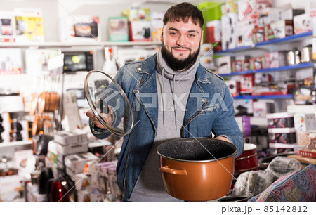 Joyful buyer chooses pot in the hardware store Joyful buyer chooses pot in the hardware store 85142812