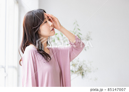 部屋の中で額に手をやる体調不良の女性 85147007