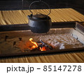 冬の古民家の囲炉裏　自在鉤に吊るされた鉄瓶と薪の炎 85147278