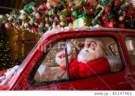 Portrait of santa claus driving a red car for...の写真素材