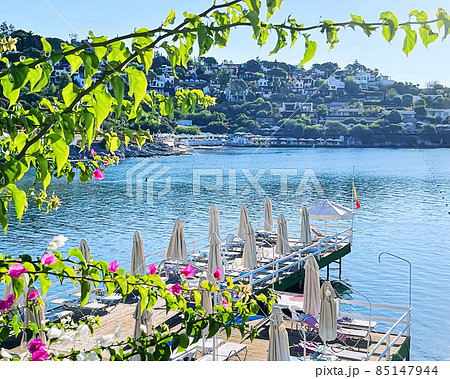 Riviera blue and summertime vacation concept. Beach pier with sunbeds and white umbrellas at luxury beachfront resort by the sea Riviera blue and summertime vacation concept. Beach pier with sunbeds and white umbrellas at luxury beachfront resort by the sea 85147944