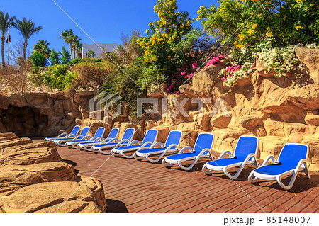 Several of sun loungers by a beautiful swimming pool. Several of sun loungers by a beautiful swimming pool. 85148007