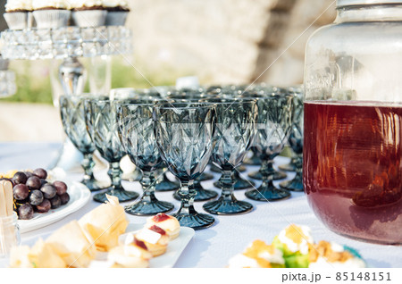 Elegant blue glasses without champagne stand in row next to canapes and snacks on picturesque background. 85148151