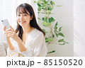 ソファに座ってスマホを使う女性 85150520