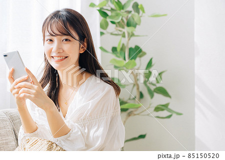 ソファに座ってスマホを使う女性 85150520