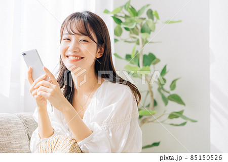 ソファに座ってスマホを使う女性 85150526