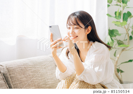 ソファに座ってスマホを見る女性 85150534