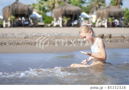 Little girl playing on the beach by the sea 85152328