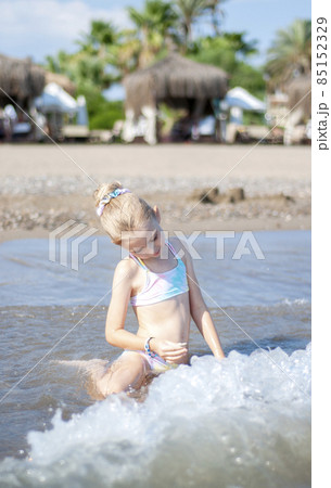 Little girl playing on the beach by the sea Little girl playing on the beach by the sea 85152329