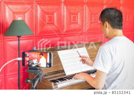 asian music instructor streaming a live video while teaching his student at home. e-learning technology, work from home concept asian music instructor streaming a live video while teaching his student at home. e-learning technology, work from home concept 85152341