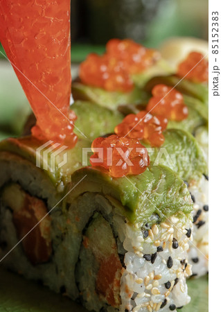 The sushi chief  at the restaurant puts red salmon caviar on the sushi rolls with avocado. Concept of Japanese and Chinese cuisine. 85152383