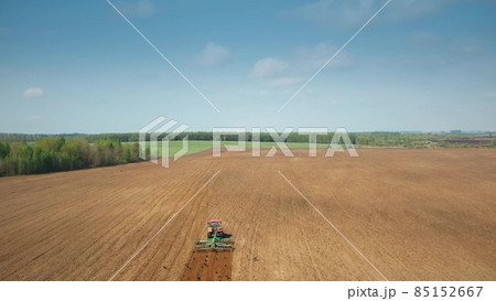 4K Aerial Flat View. Birds In Flock Following For Tractor That Plowing Field In Spring Season. Beginning Of Agricultural Spring Season. Cultivator Pulled By A Tractor In Countryside Rural Field 85152667