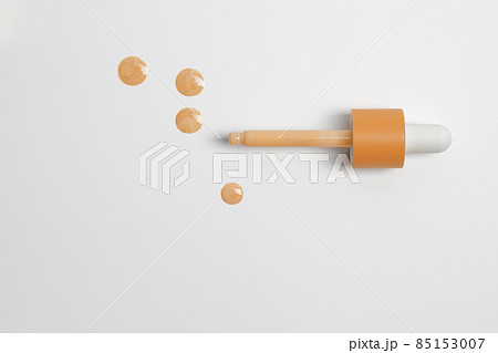 Drops of liquid skin tint serum foundation applied from dropper on white background Drops of liquid skin tint serum foundation applied from dropper on white background 85153007